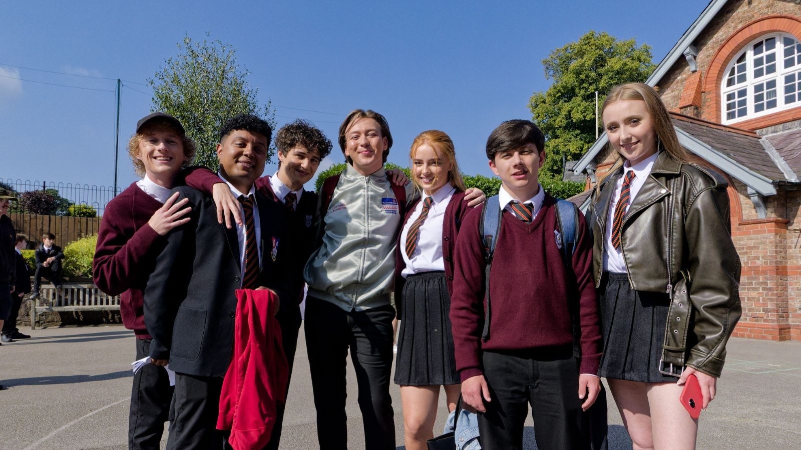 G'wed cast in school uniform in front of a school