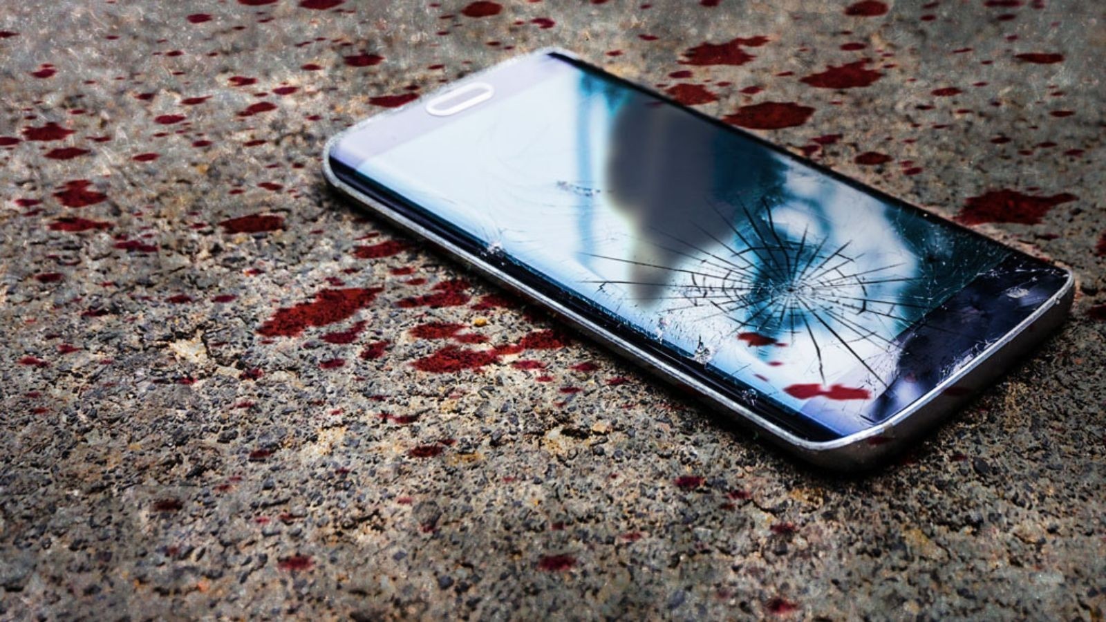 Image of phone on the ground covered with blood splatters