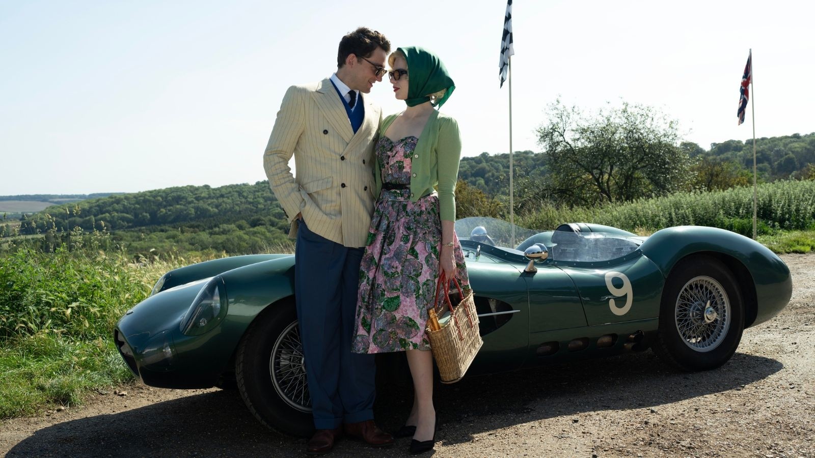 Lucy Boynton and Laurie Davies stood in front of a race car in A Cruel Love: The Ruth Ellis story 